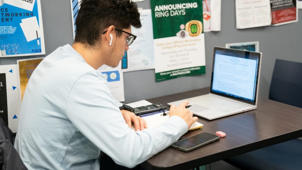 student with headphones in ears working on laptop